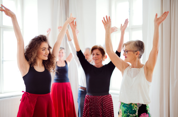 A group of senior people attending dancing class with dance teacher.