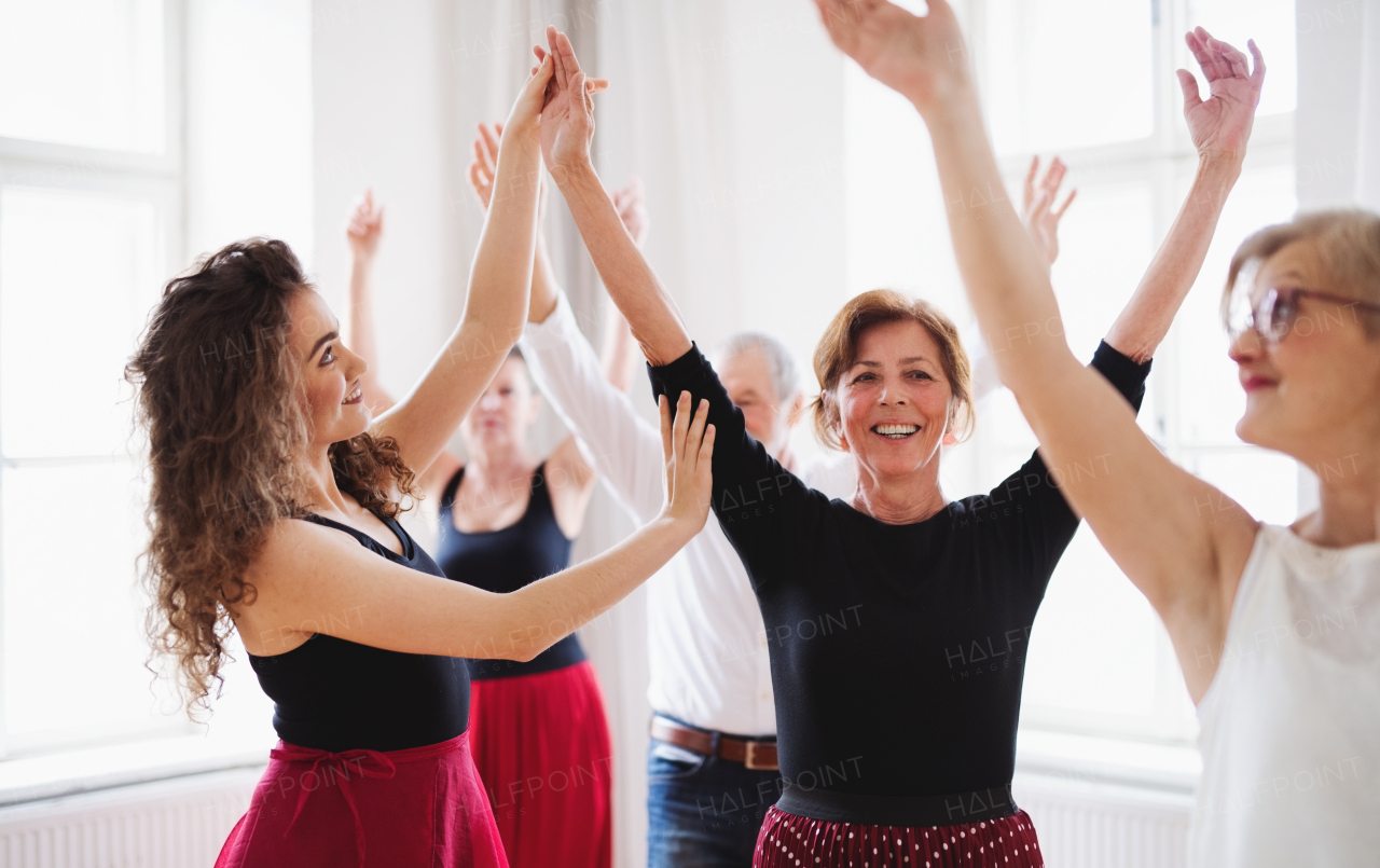 A group of senior people attending dancing class with dance teacher.