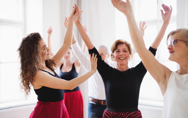 A group of senior people attending dancing class with dance teacher.