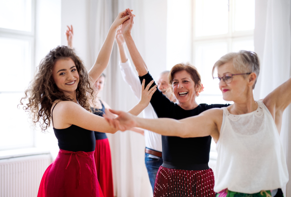 A group of senior people attending dancing class with dance teacher.