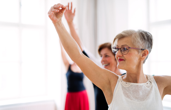 A group of female seniors attending dancing class with dance teacher.