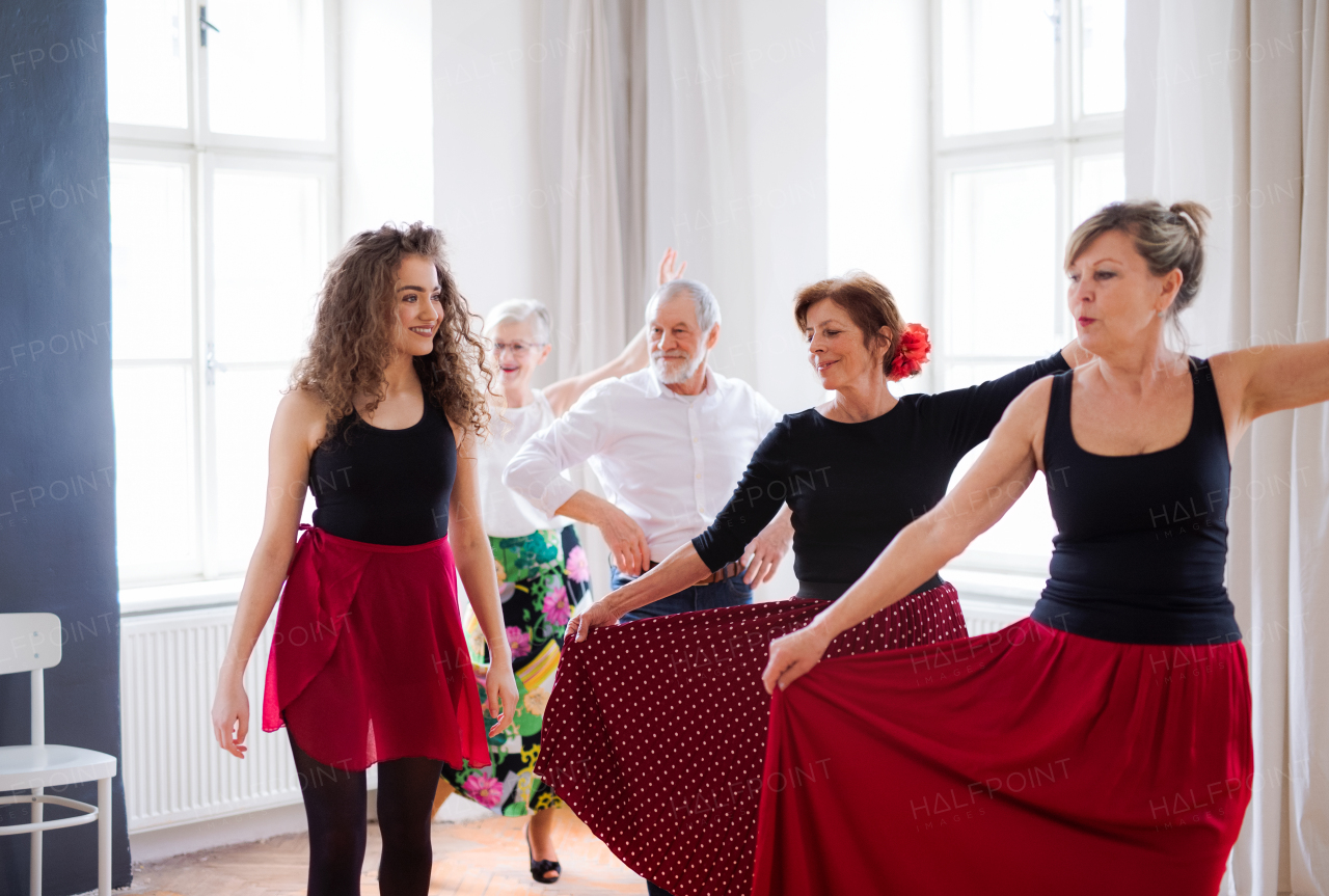 A group of senior people attending dancing class with dance teacher.