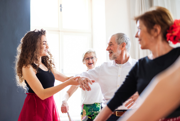 A group of senior people attending dancing class with dance teacher.