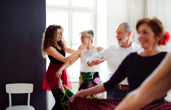 A group of senior people attending dancing class with dance teacher.