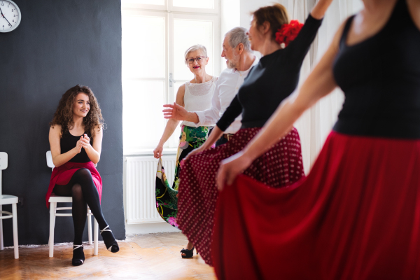 A group of senior people attending dancing class with dance teacher.