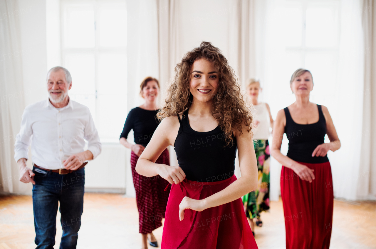 A group of senior people attending dancing class with dance teacher.