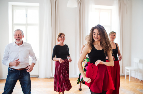 A group of senior people attending dancing class with dance teacher.