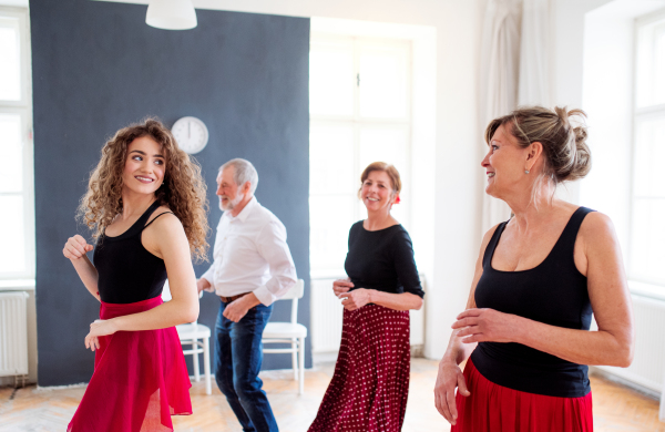 A group of senior people attending dancing class with dance teacher.