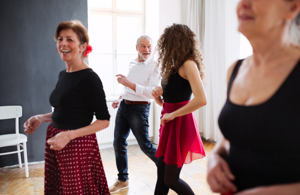 A group of senior people attending dancing class with dance teacher.