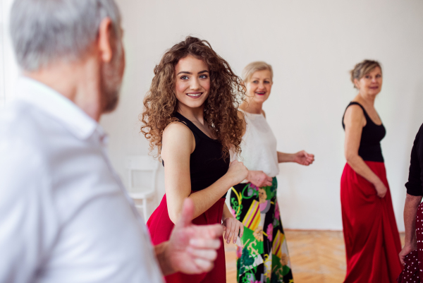 A group of senior people attending dancing class with dance teacher.