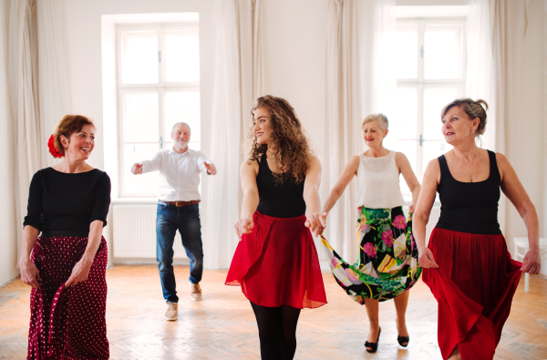 A group of senior people attending dancing class with dance teacher.