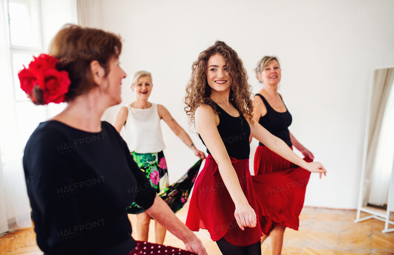 A group of senior women attending dancing class with dance teacher.