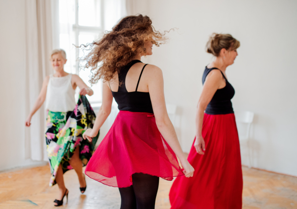 A group of female seniors attending dancing class with dance teacher.