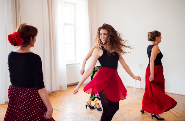 A group of senior people attending dancing class with dance teacher.