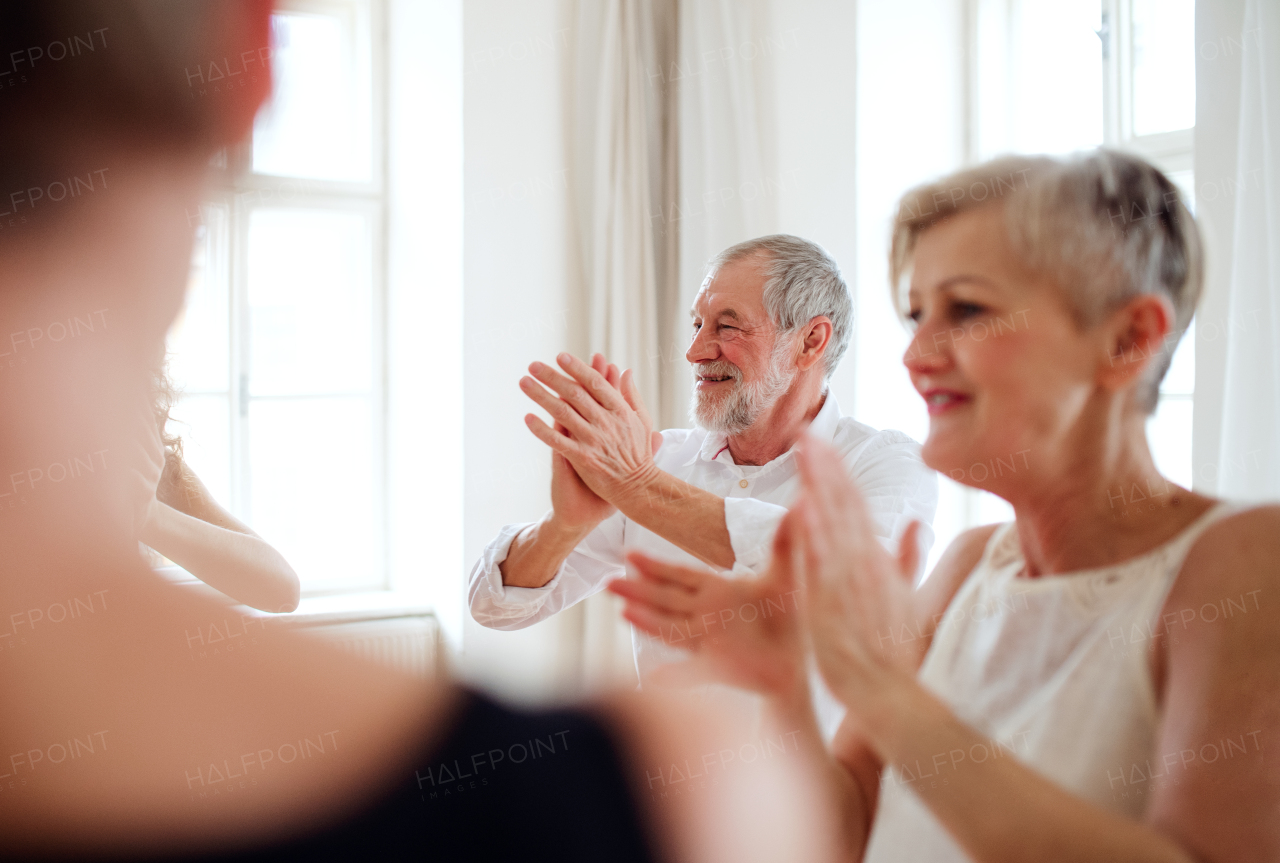 A group of senior people attending dancing class with dance teacher.