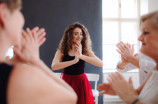 A group of senior people attending dancing class with dance teacher.