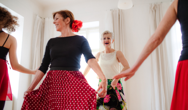 A group of senior women attending dancing class with dance teacher.