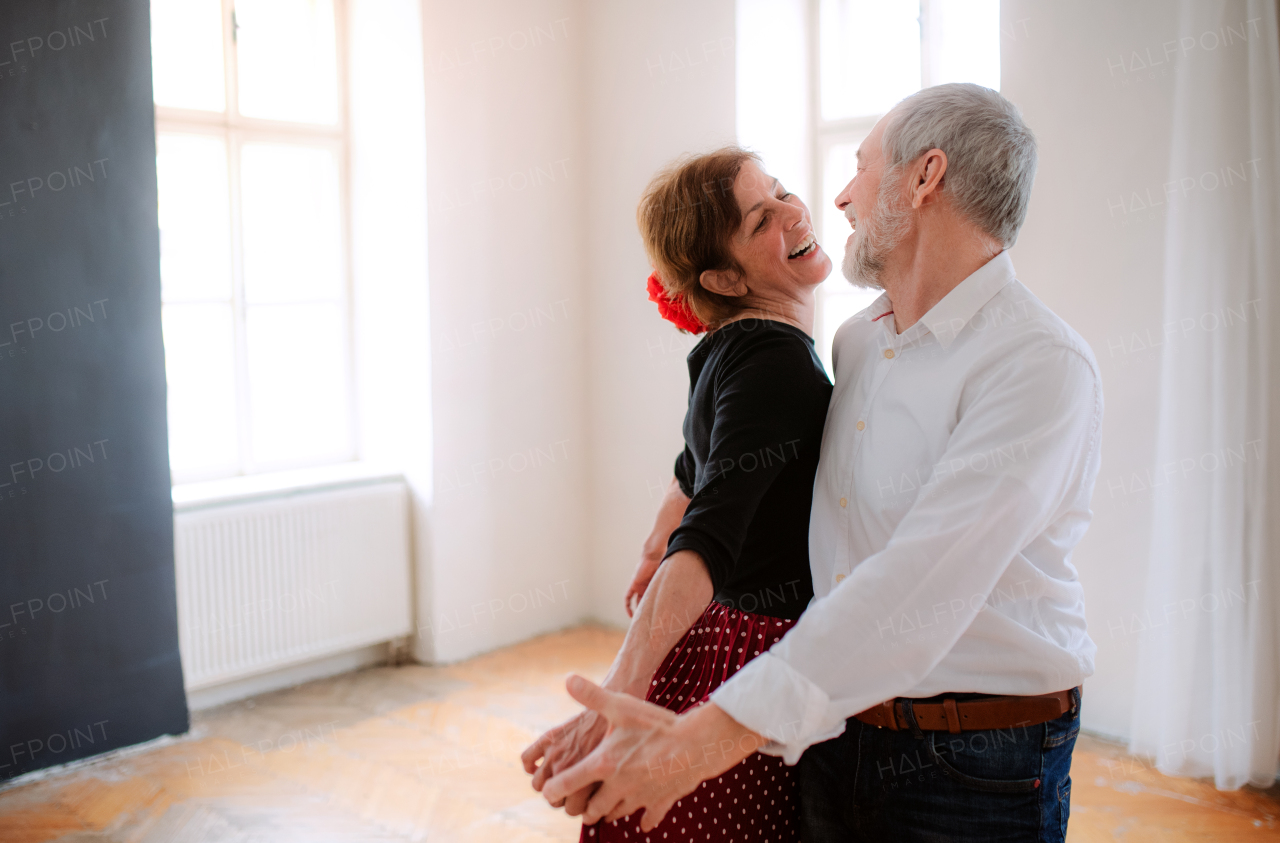 Happy senior couple in love attending dancing class in community center.