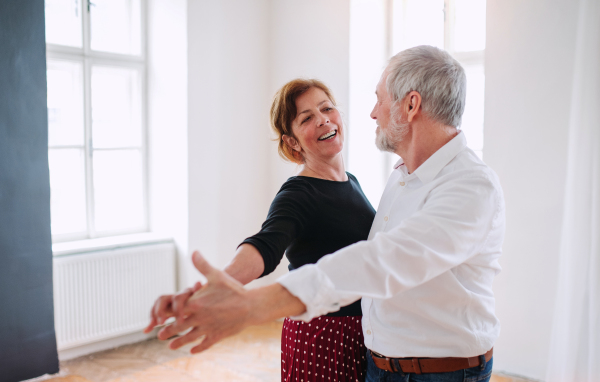 Happy senior couple in love attending dancing class in community center.