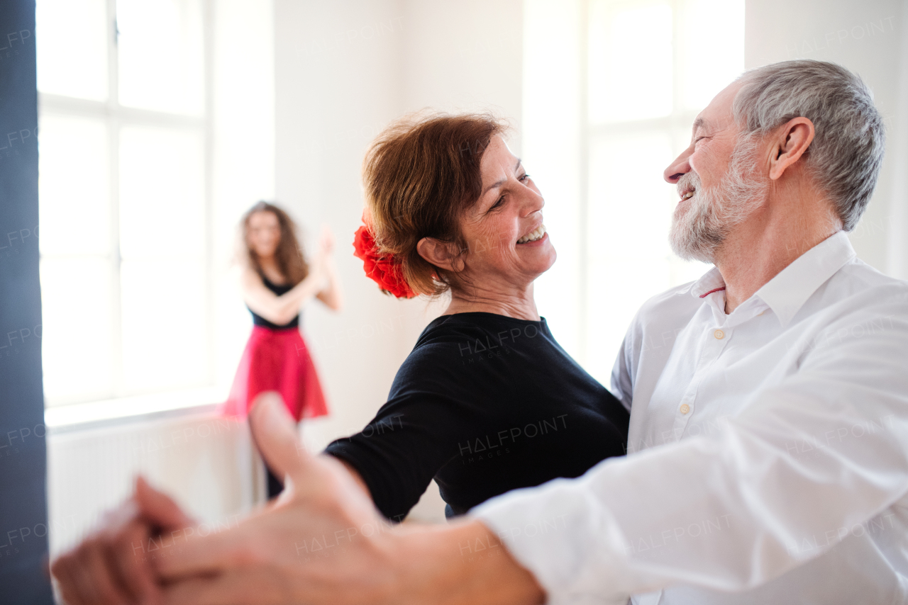 A group of senior people attending dancing class with young dance teacher.