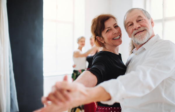 Happy senior couple in love attending dancing class in community center.