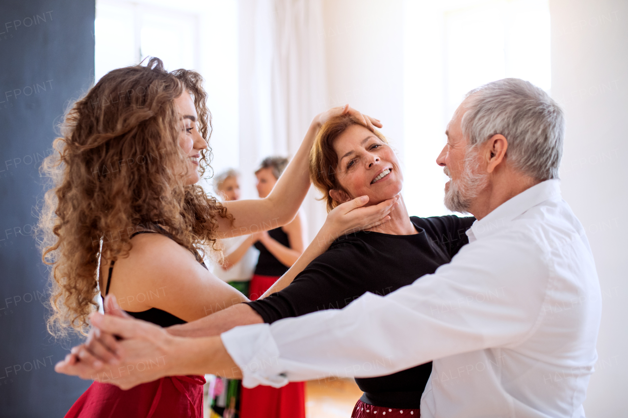 A group of senior people attending dancing class with dance teacher.