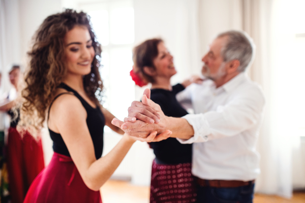 A group of senior people attending dancing class with dance teacher.