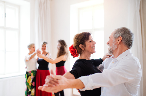 A group of senior people attending dancing class with young dance teacher.