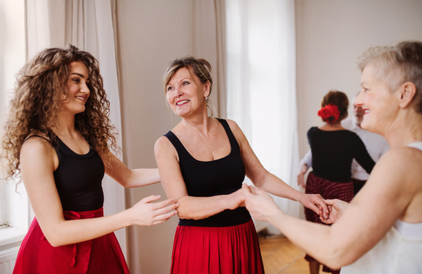 A group of senior people attending dancing class with dance teacher.