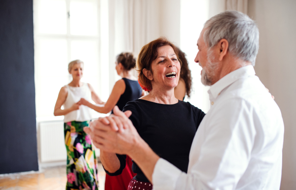 A group of senior people attending dancing class with dance teacher.