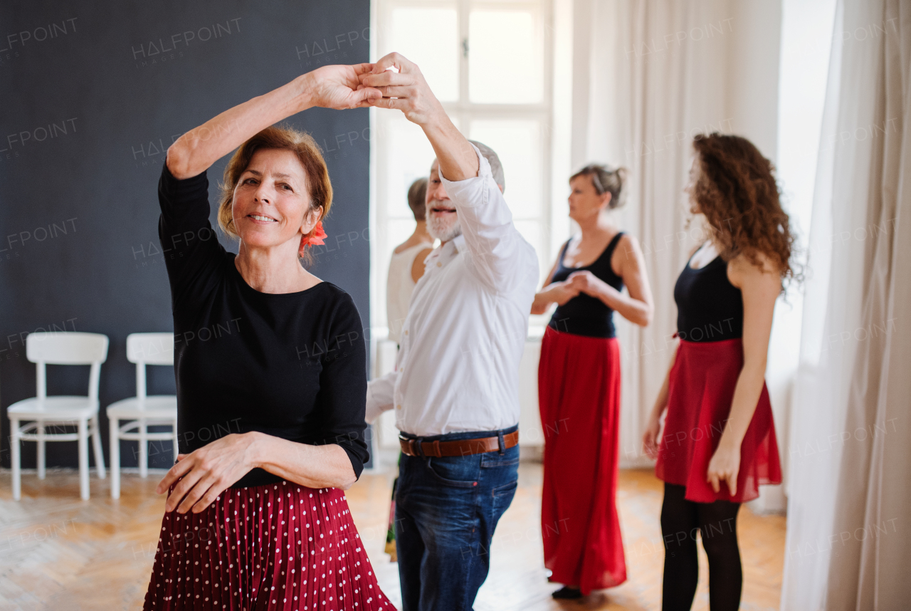 A group of senior people attending dancing class with dance teacher.