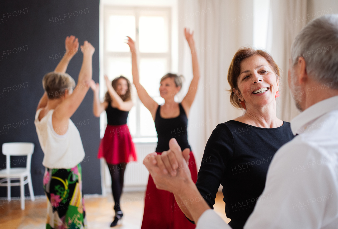 A group of senior people attending dancing class with dance teacher.