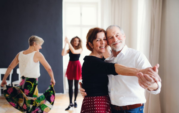 A group of senior people attending dancing class with dance teacher.