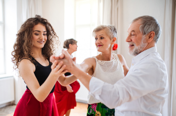 A group of senior people attending dancing class with dance teacher.