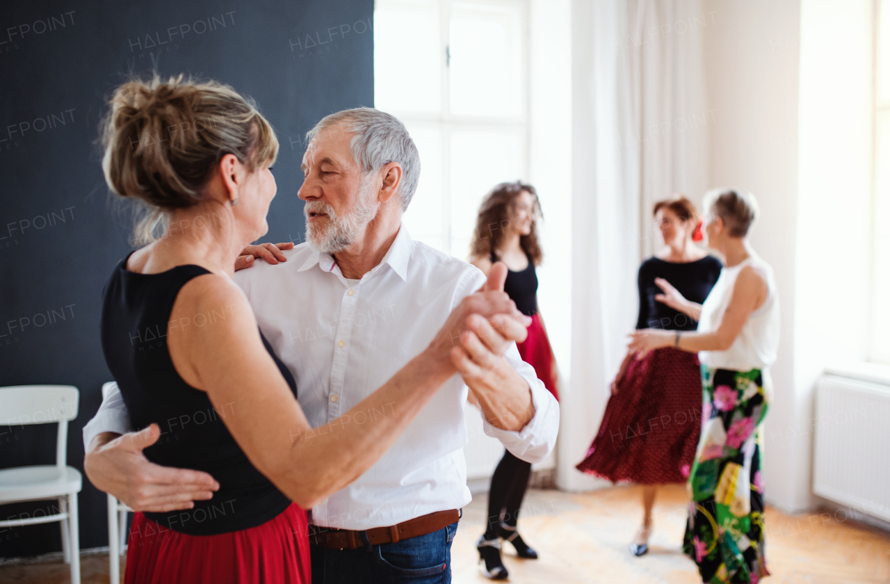 A group of senior people attending dancing class with dance teacher.