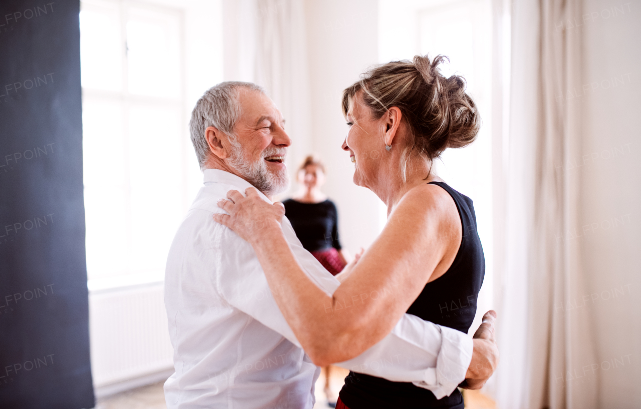 Happy senior couple in love attending dancing class in community center.