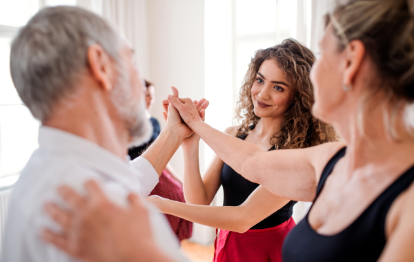 A group of senior people attending dancing class with dance teacher.