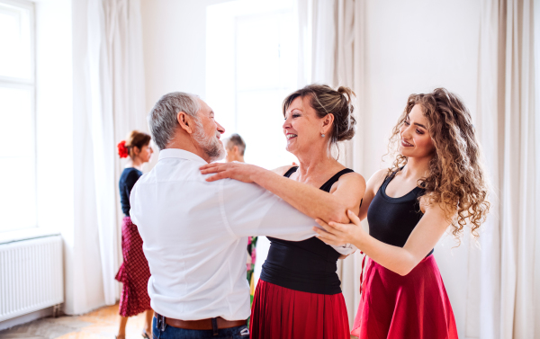 A group of senior people attending dancing class with dance teacher.