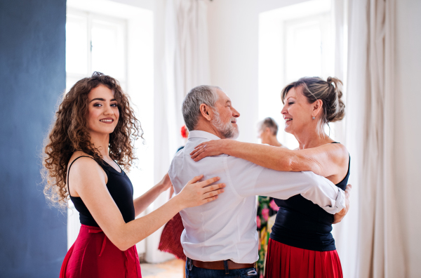 A group of senior people attending dancing class with dance teacher.