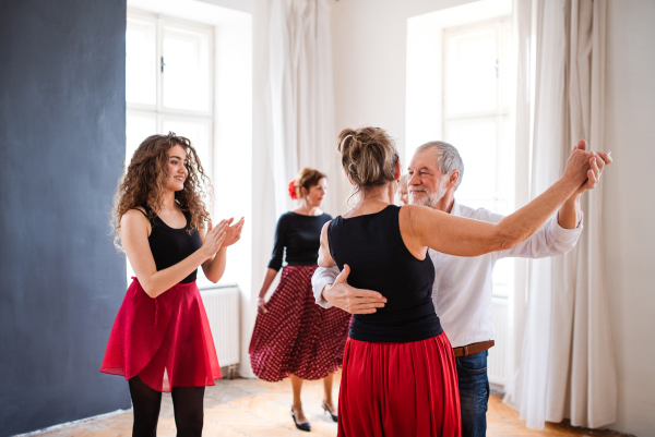 A group of senior people attending dancing class with dance teacher.