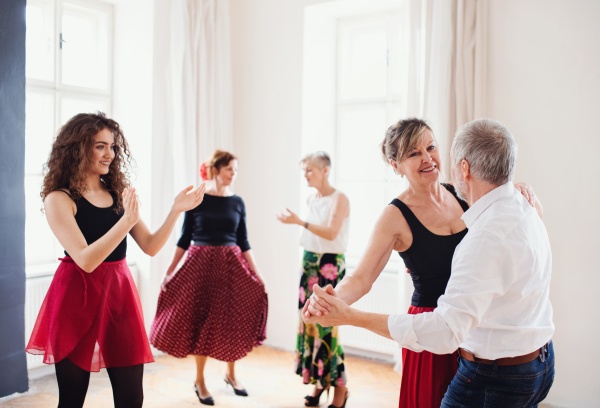 A group of senior people attending dancing class with dance teacher.