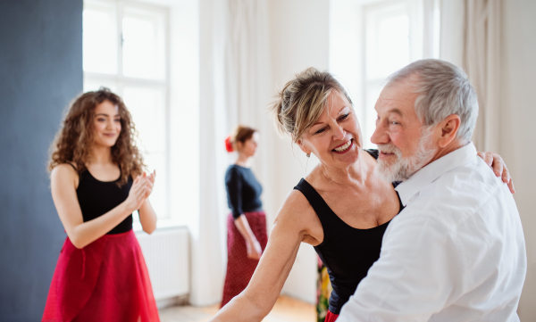 A group of senior people attending dancing class with dance teacher.