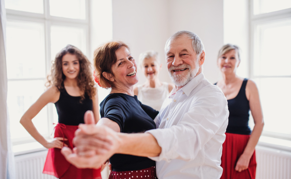 A group of senior people attending dancing class with dance teacher.