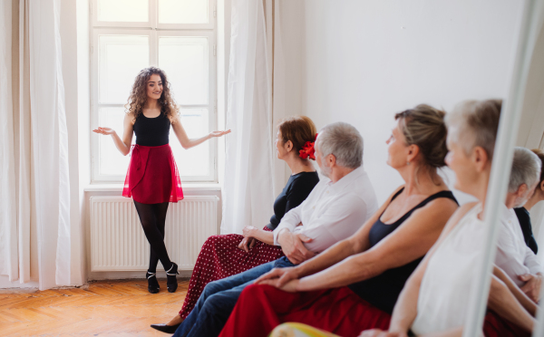 A group of senior people attending dancing class with dance teacher.