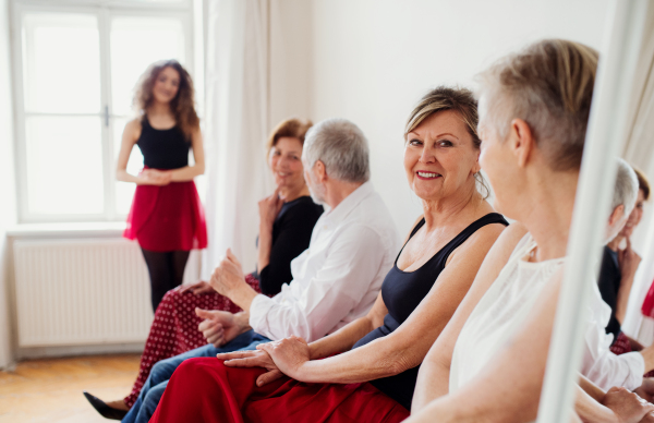 A group of senior people attending dancing class with dance teacher.