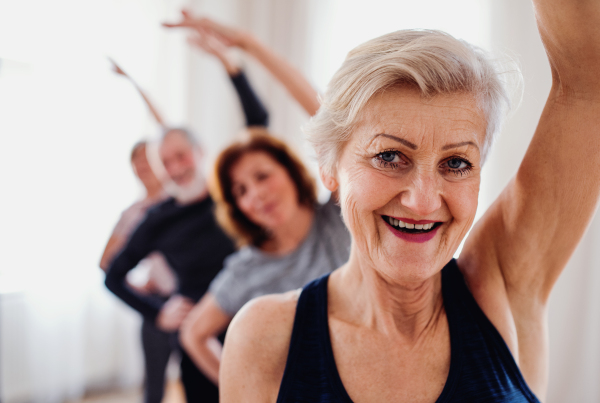 Group of active senior people doing exercise in community center club.