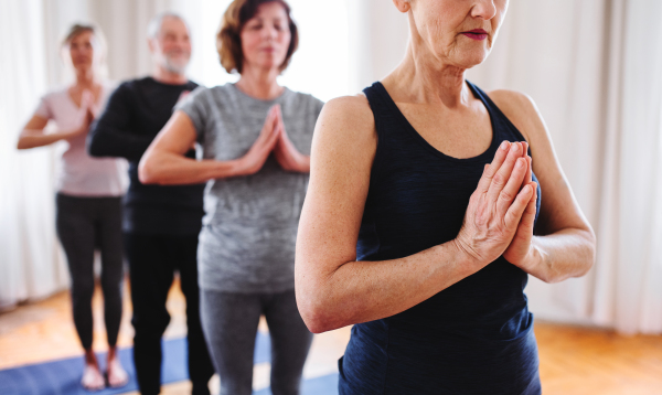 A group of active senior people doing yoga exercise in community center club.