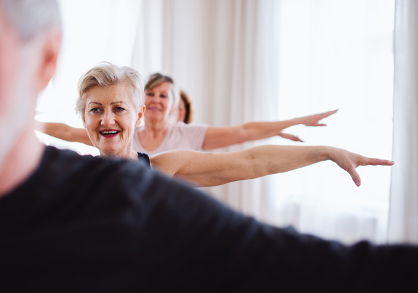 Group of active senior people doing exercise in community center club.