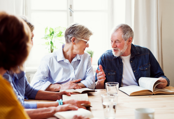 Senior people in bible reading group in community center club, praying.