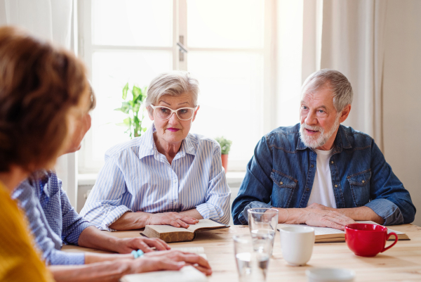 Senior people in bible reading group in community center club, praying.